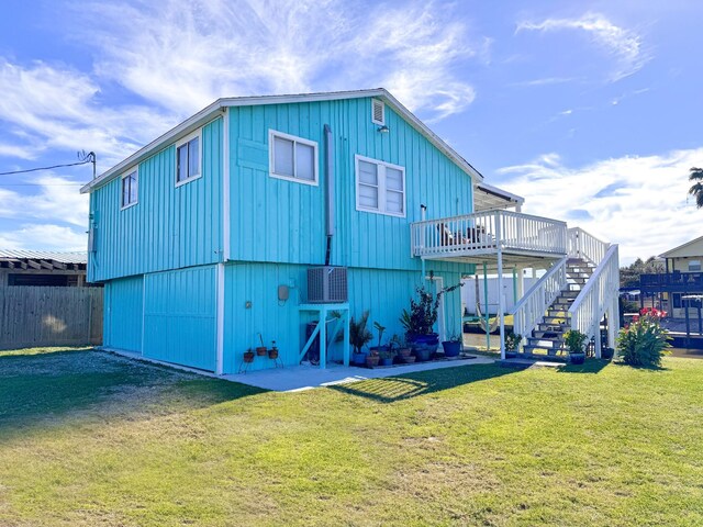 rear view of house featuring a deck, central AC, and a lawn