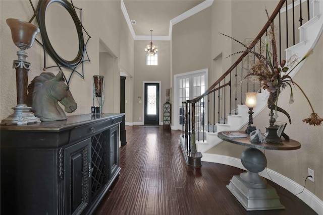 entrance foyer featuring dark wood-type flooring, a high ceiling, french doors, an inviting chandelier, and ornamental molding