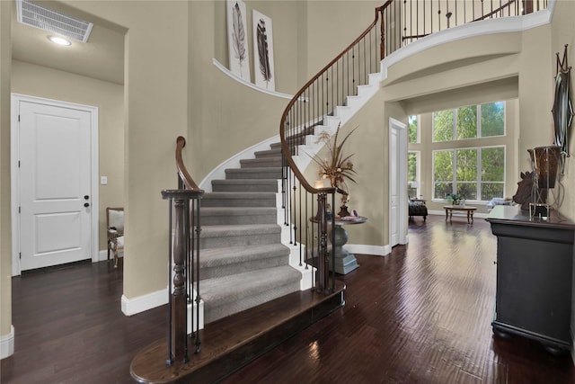 staircase with wood-type flooring and a towering ceiling