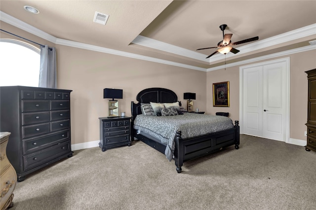 bedroom featuring ceiling fan, crown molding, a tray ceiling, light carpet, and a closet