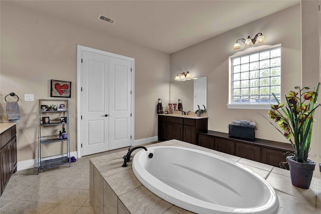 bathroom with vanity, tile patterned floors, and tiled tub