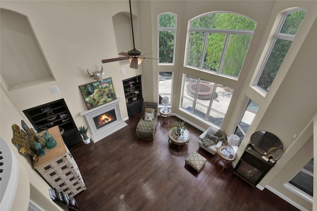 living room featuring ceiling fan, a towering ceiling, and dark wood-type flooring