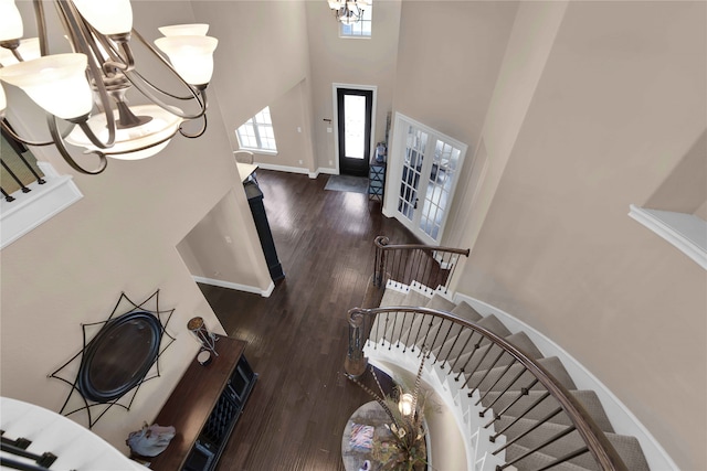 foyer entrance with dark hardwood / wood-style flooring, a towering ceiling, an inviting chandelier, and french doors