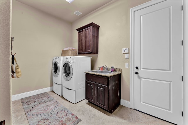 clothes washing area with cabinets, sink, light tile patterned floors, and washer and dryer