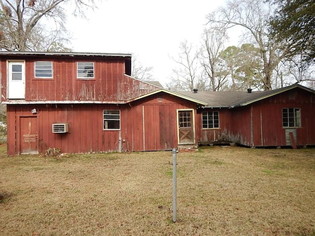 back of house with an AC wall unit and a lawn