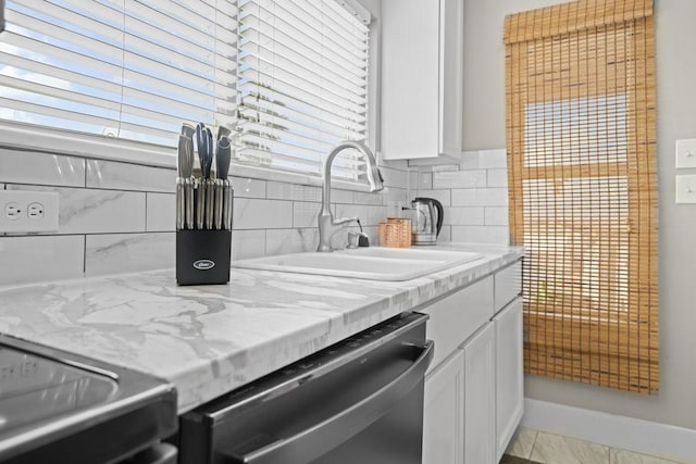 kitchen featuring white cabinetry, dishwasher, sink, light stone counters, and backsplash