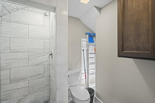 bathroom featuring tiled shower, vaulted ceiling, and toilet