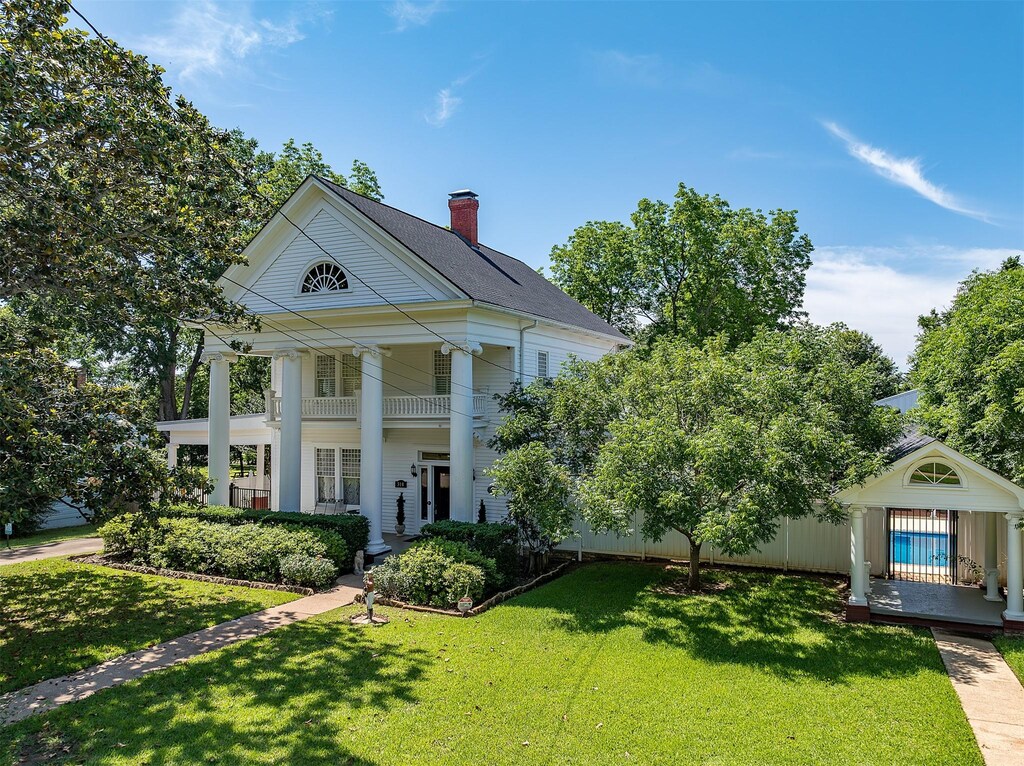 310 E Kolstad, Palestine, TX 75801 - greek revival house with a balcony, a chimney, and a front lawn