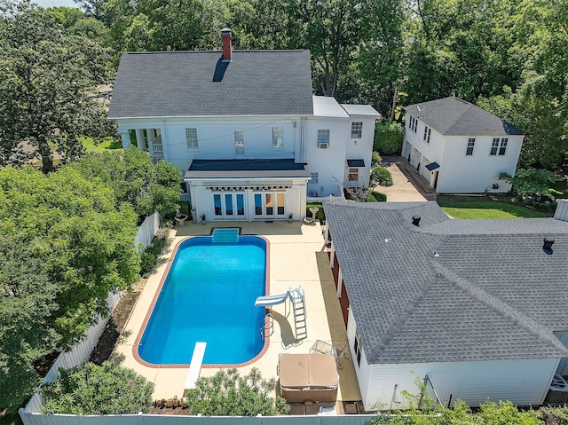 rear view of house featuring a fenced in pool, french doors, a patio, a chimney, and a fenced backyard