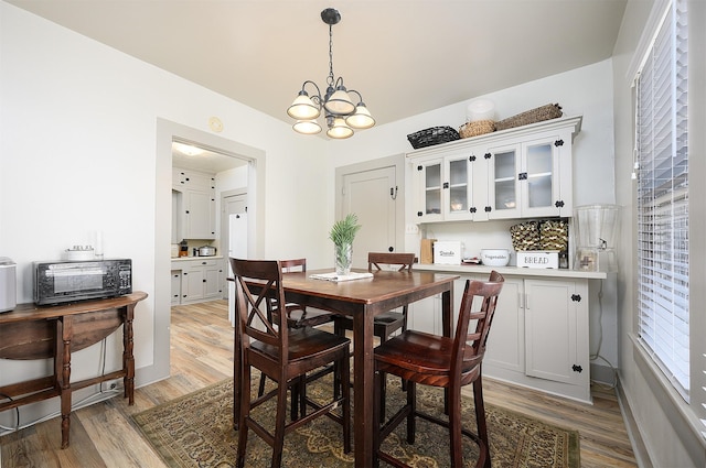 dining room with light wood-style floors and an inviting chandelier