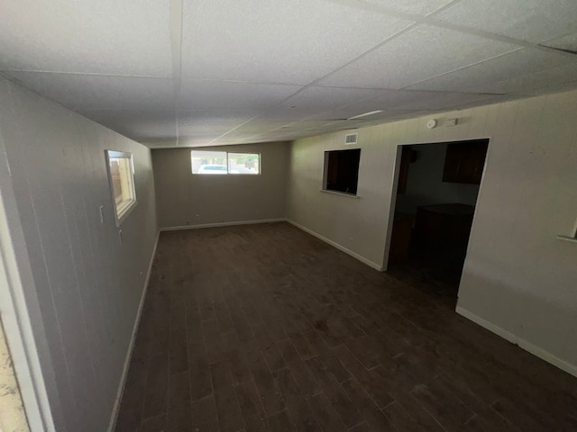 empty room featuring a drop ceiling and dark hardwood / wood-style flooring