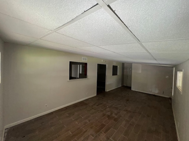 basement featuring a drop ceiling and dark hardwood / wood-style flooring