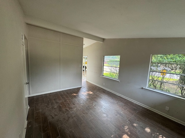 empty room with lofted ceiling with beams and dark hardwood / wood-style floors