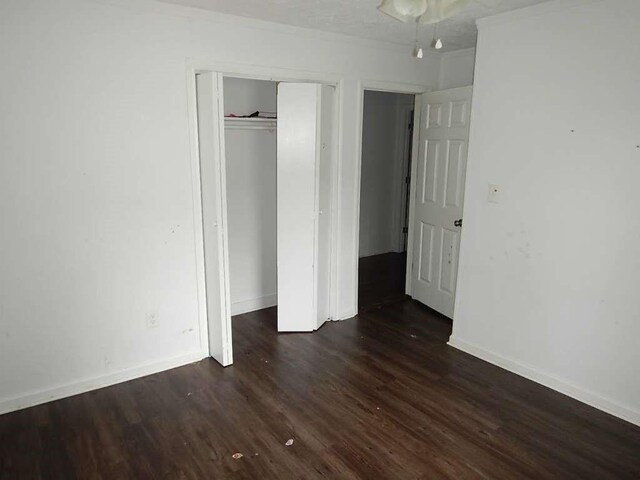 unfurnished bedroom with dark hardwood / wood-style flooring and a closet