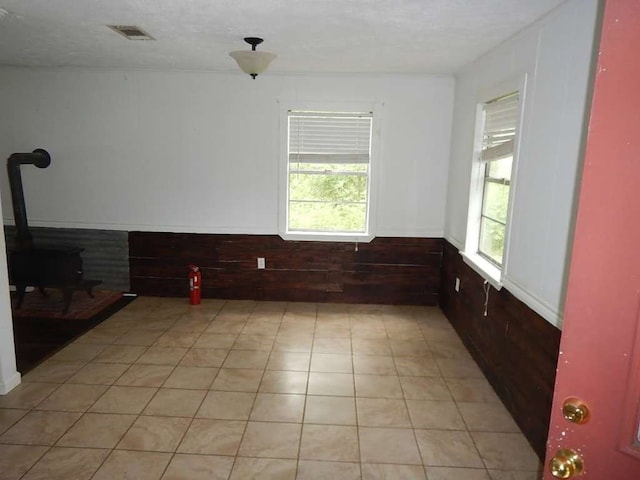 tiled empty room featuring a wood stove