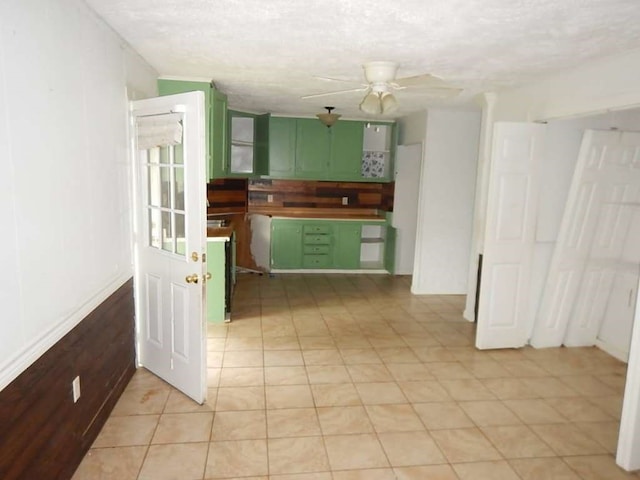 kitchen with a textured ceiling, green cabinetry, light tile patterned floors, and ceiling fan