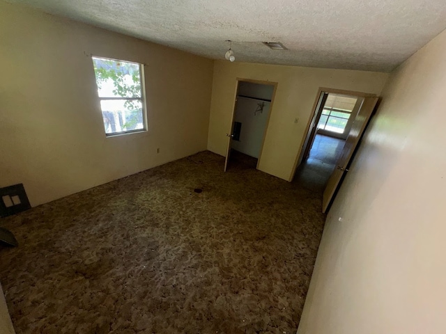 unfurnished bedroom featuring carpet floors, a textured ceiling, and lofted ceiling