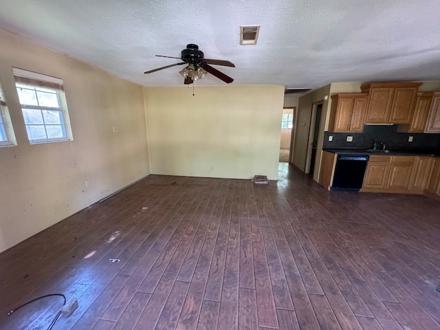 interior space featuring ceiling fan, a textured ceiling, backsplash, dark hardwood / wood-style floors, and black dishwasher