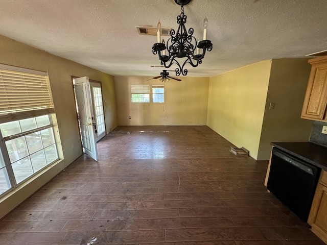 unfurnished dining area with ceiling fan with notable chandelier, a textured ceiling, and dark hardwood / wood-style floors