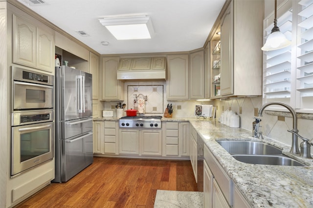 kitchen featuring sink, decorative light fixtures, stainless steel appliances, light stone countertops, and dark hardwood / wood-style flooring