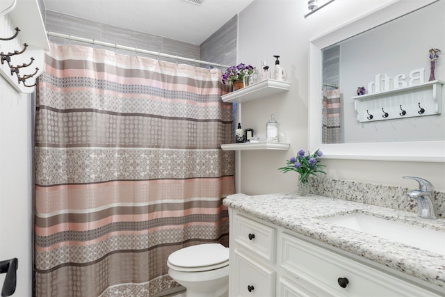 bathroom with walk in shower, vanity, and toilet