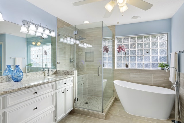 bathroom featuring ceiling fan, tile walls, vanity, and independent shower and bath