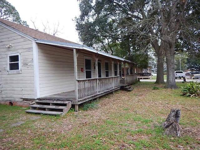 view of side of home with a yard and covered porch