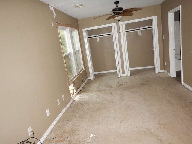 unfurnished bedroom with two closets and ceiling fan