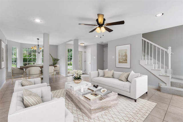 tiled living room featuring ceiling fan with notable chandelier and a wealth of natural light