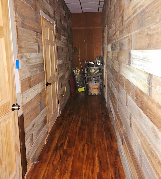 hall with dark wood-type flooring and wood walls