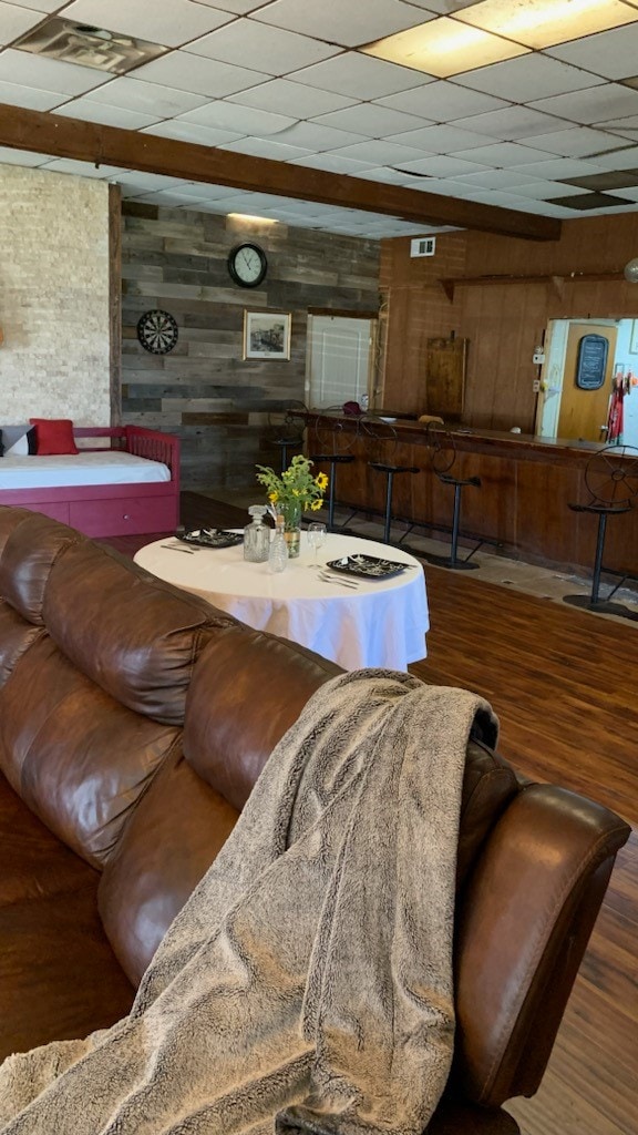 living room featuring a paneled ceiling, wooden walls, and hardwood / wood-style floors