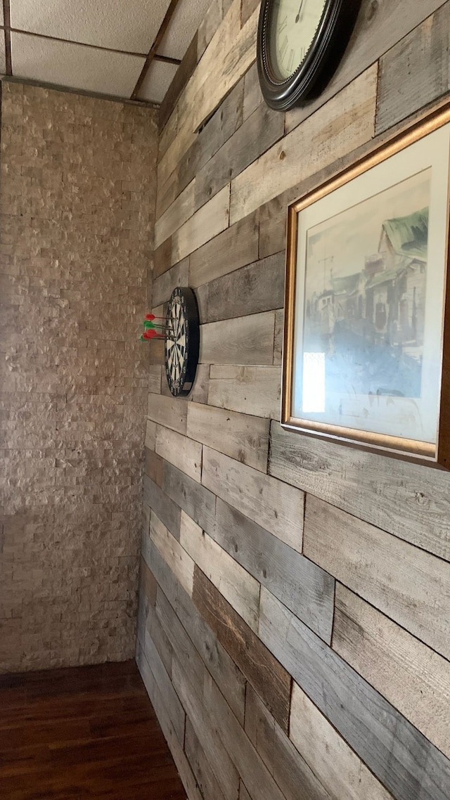 details featuring hardwood / wood-style floors, a drop ceiling, and wood walls