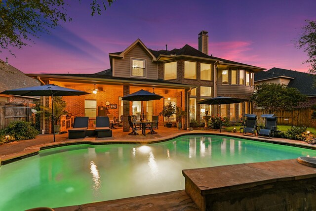 pool at dusk featuring a patio