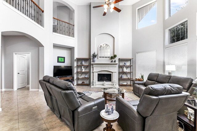 living room with a towering ceiling, light tile patterned floors, and ceiling fan