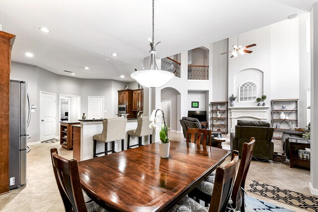 tiled dining space with ceiling fan and a high ceiling