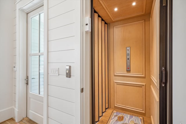 interior space featuring elevator, wooden walls, hardwood / wood-style floors, and wooden ceiling