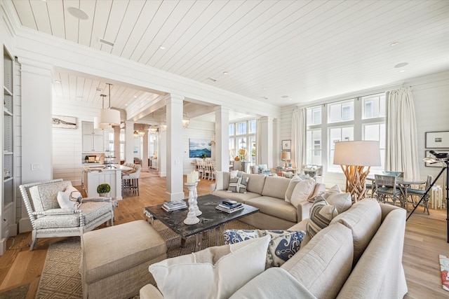 living room featuring light hardwood / wood-style floors, ornate columns, and wood ceiling