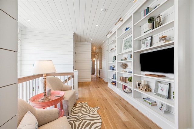 living area featuring light hardwood / wood-style floors, wood ceiling, and wood walls