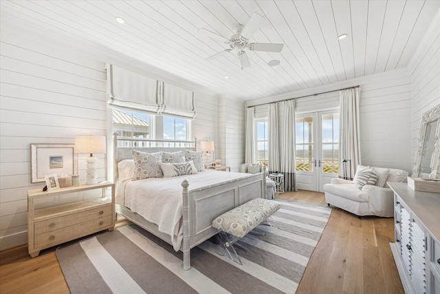 bedroom featuring ceiling fan, wood walls, light wood-type flooring, and wood ceiling