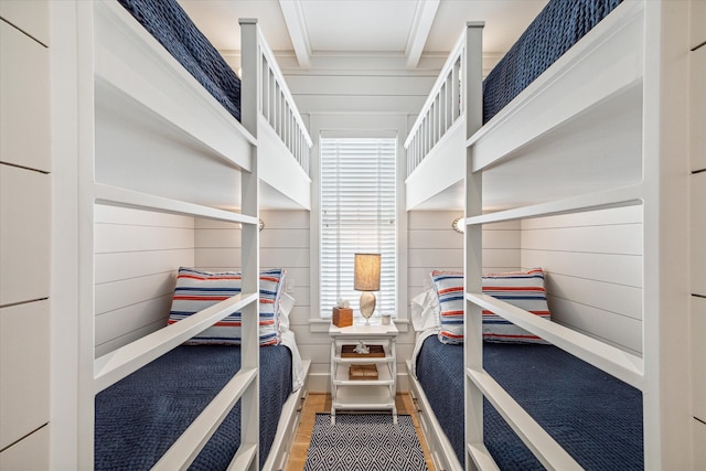 bedroom with beam ceiling, wooden walls, and wood-type flooring