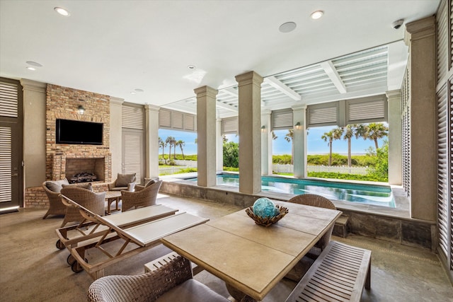 sunroom with decorative columns and an outdoor brick fireplace