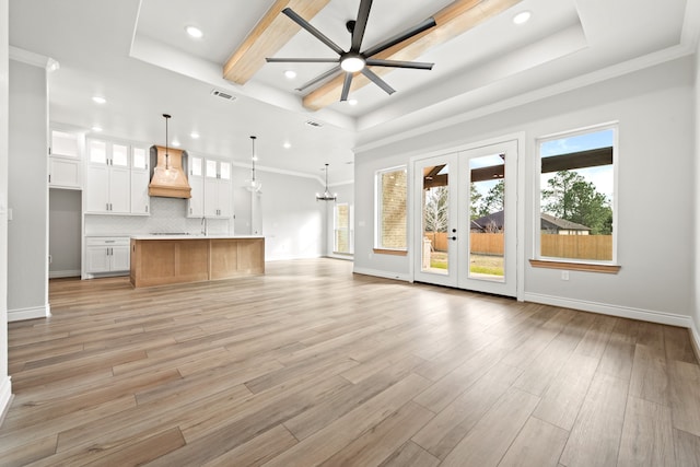 unfurnished living room with light hardwood / wood-style floors, ceiling fan, a raised ceiling, and crown molding