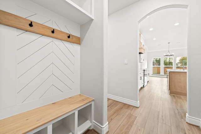 mudroom featuring sink, light wood-type flooring, a chandelier, and ornamental molding