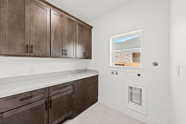 clothes washing area featuring washer hookup, light tile patterned flooring, electric dryer hookup, and cabinets