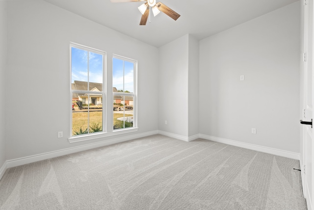 empty room featuring ceiling fan, light colored carpet, and a wealth of natural light