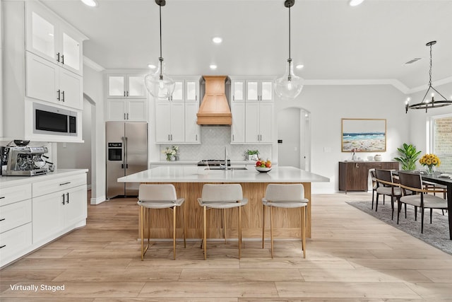 kitchen featuring a center island with sink, custom exhaust hood, stainless steel appliances, and white cabinets