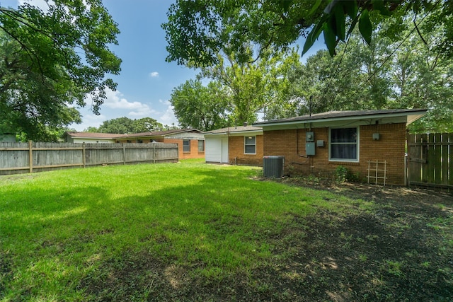 back of property with a yard, brick siding, central AC unit, and a fenced backyard