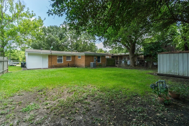 rear view of house with brick siding, fence, central AC, and a yard