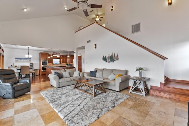 living room featuring ceiling fan with notable chandelier and high vaulted ceiling