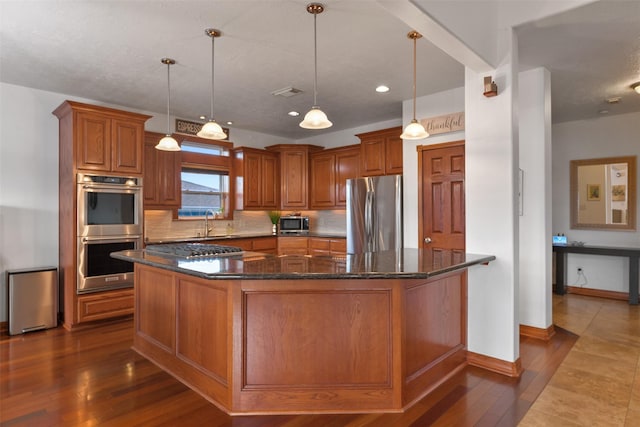 kitchen with hanging light fixtures, decorative backsplash, stainless steel appliances, and a kitchen island